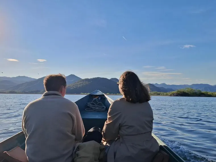 A couple in a small boat looking over the water
