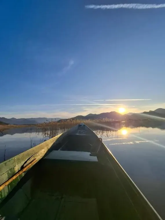 View over the boat bow across calm water at sunset