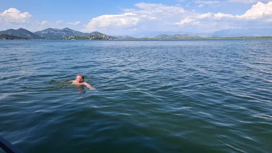 A guest swimming in the open lake with mountains behind
